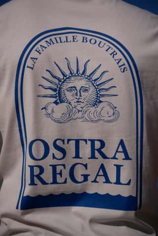 Détail de la sérigraphie bleue au dos du t-shirt Ostra Regal : le soleil sous l'arche et « La Famille Boutrais »
